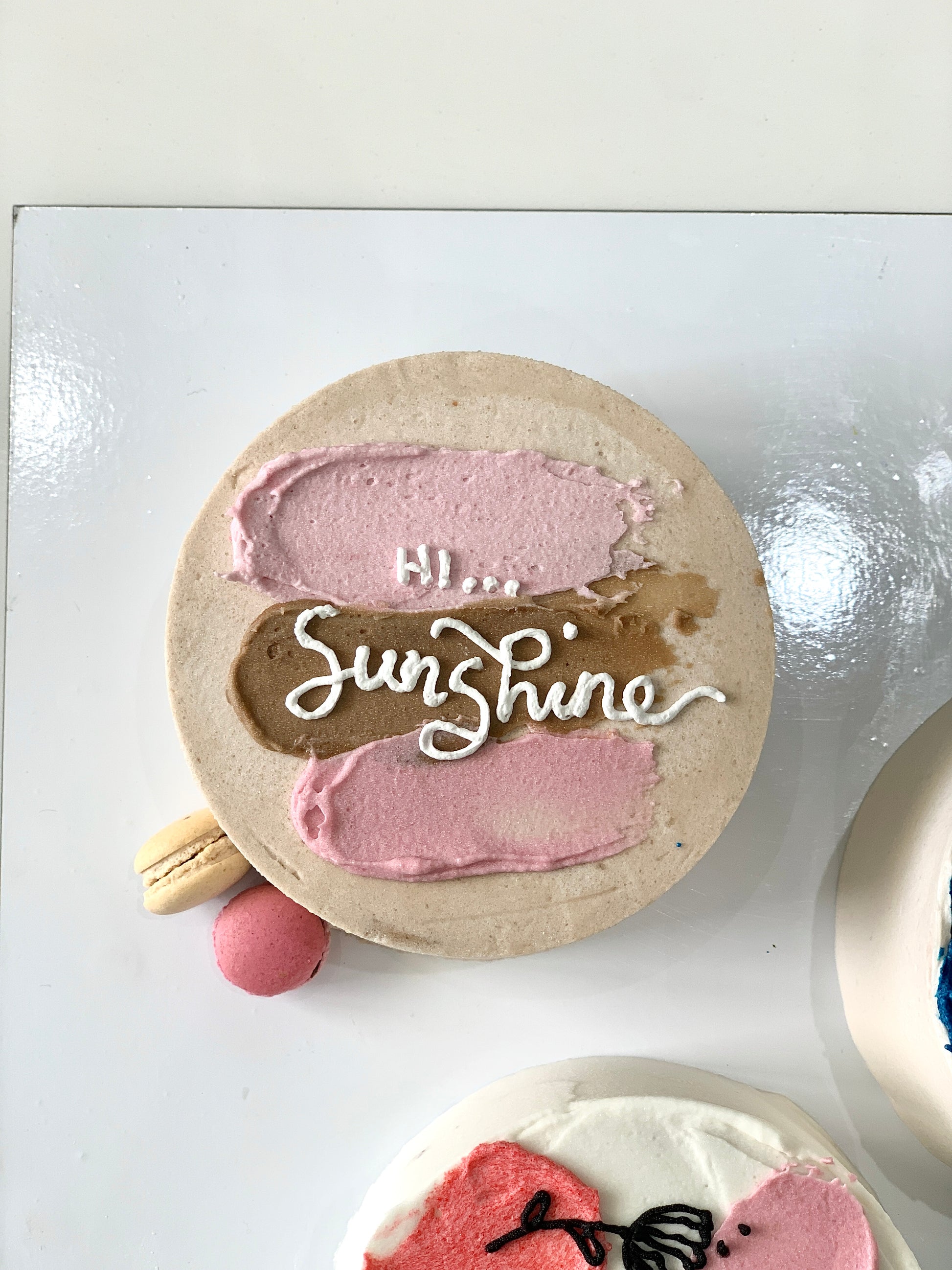 Colorful bento cakes from The Sinful Spoon with decorative frosting and vibrant toppings on a white plate.