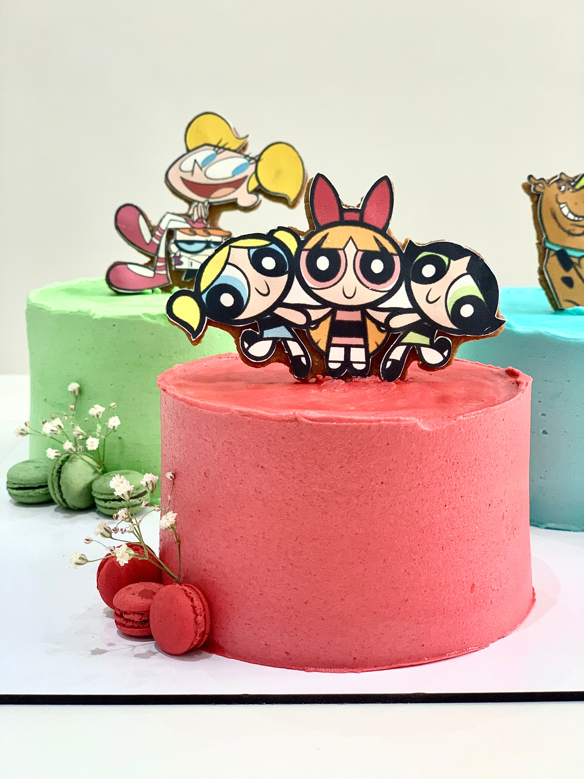 Decorative festive cakes from The Sinful Spoon with colorful icing and holiday-themed designs on a white background.
