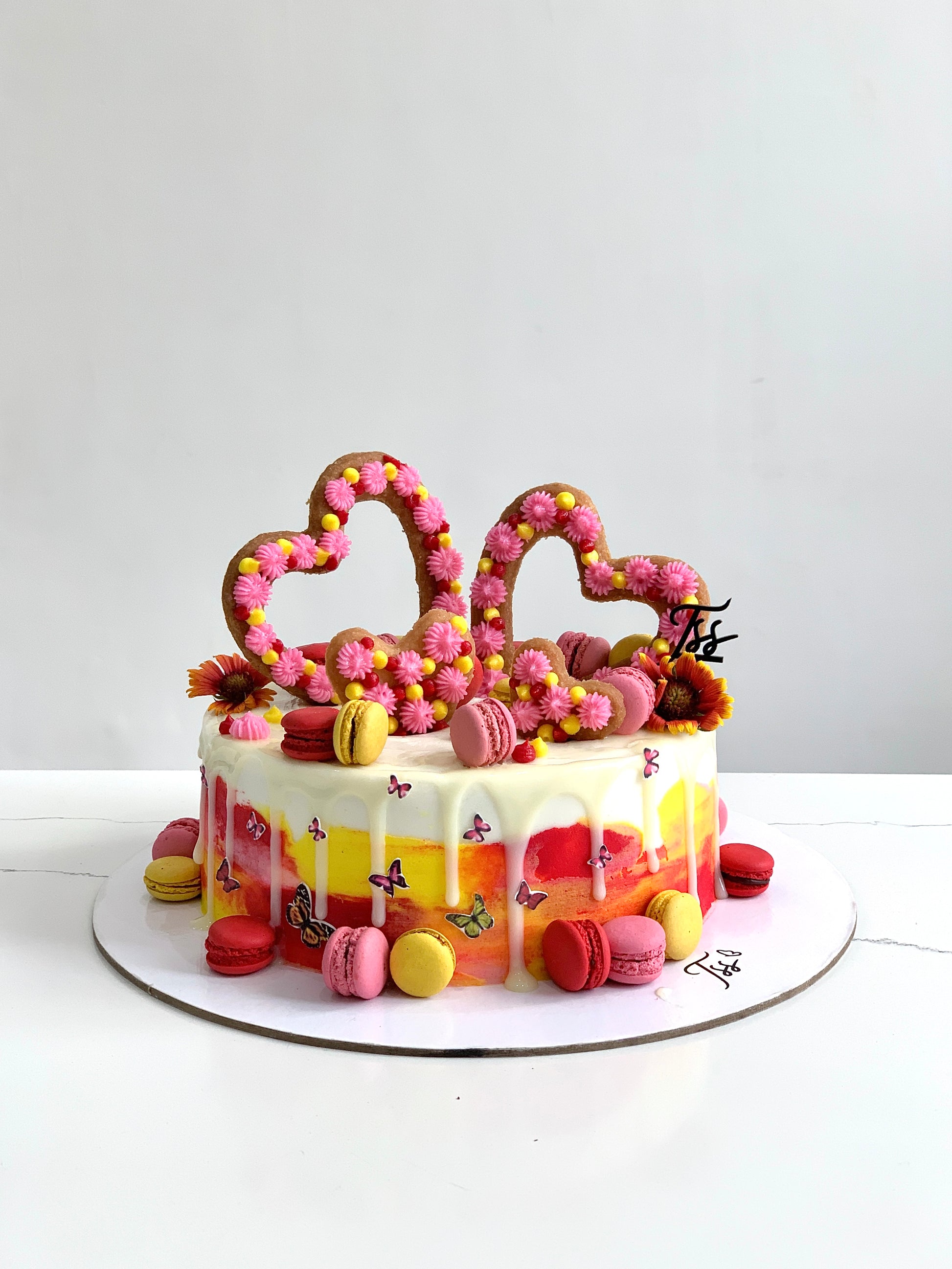 Edible paper cake topper with baby girl design from The Sinful Spoon, featuring colorful decorative elements on a cake.