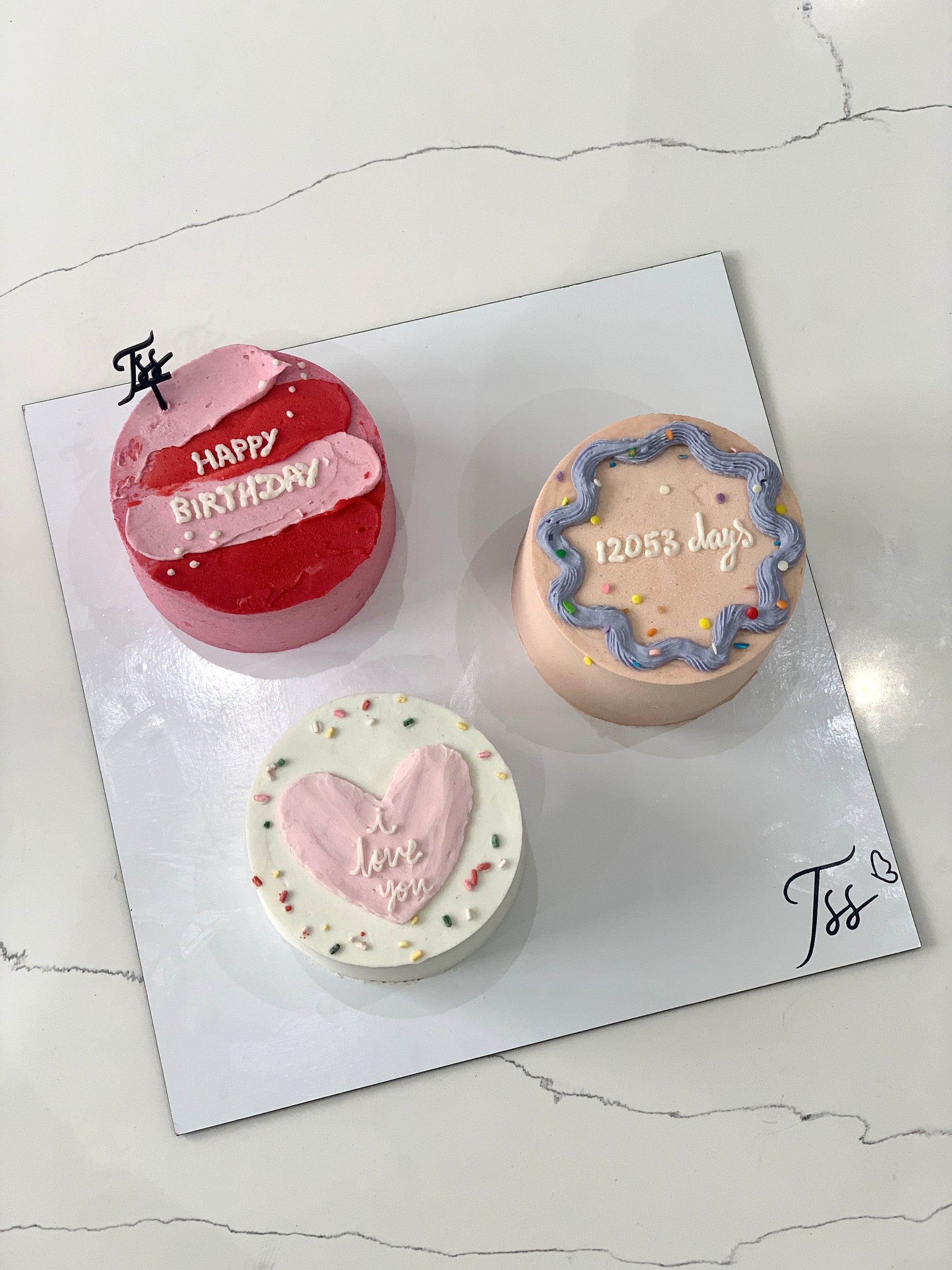 Assorted combo cakes from The Sinful Spoon with colorful frosting and decorative toppings on a white plate.