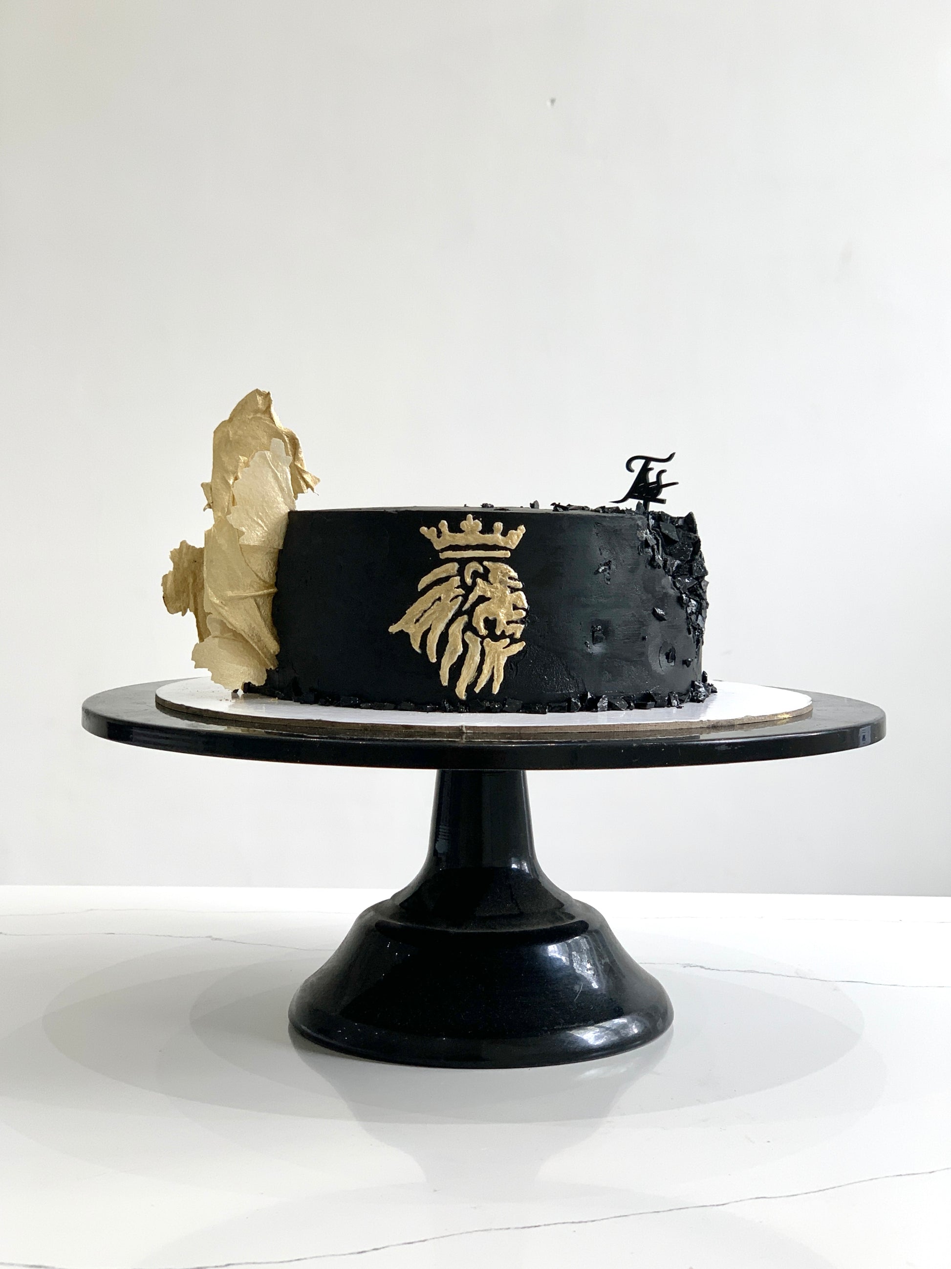 A classic cake from The Sinful Spoon with a smooth frosting and decorative toppings, displayed on a plate.