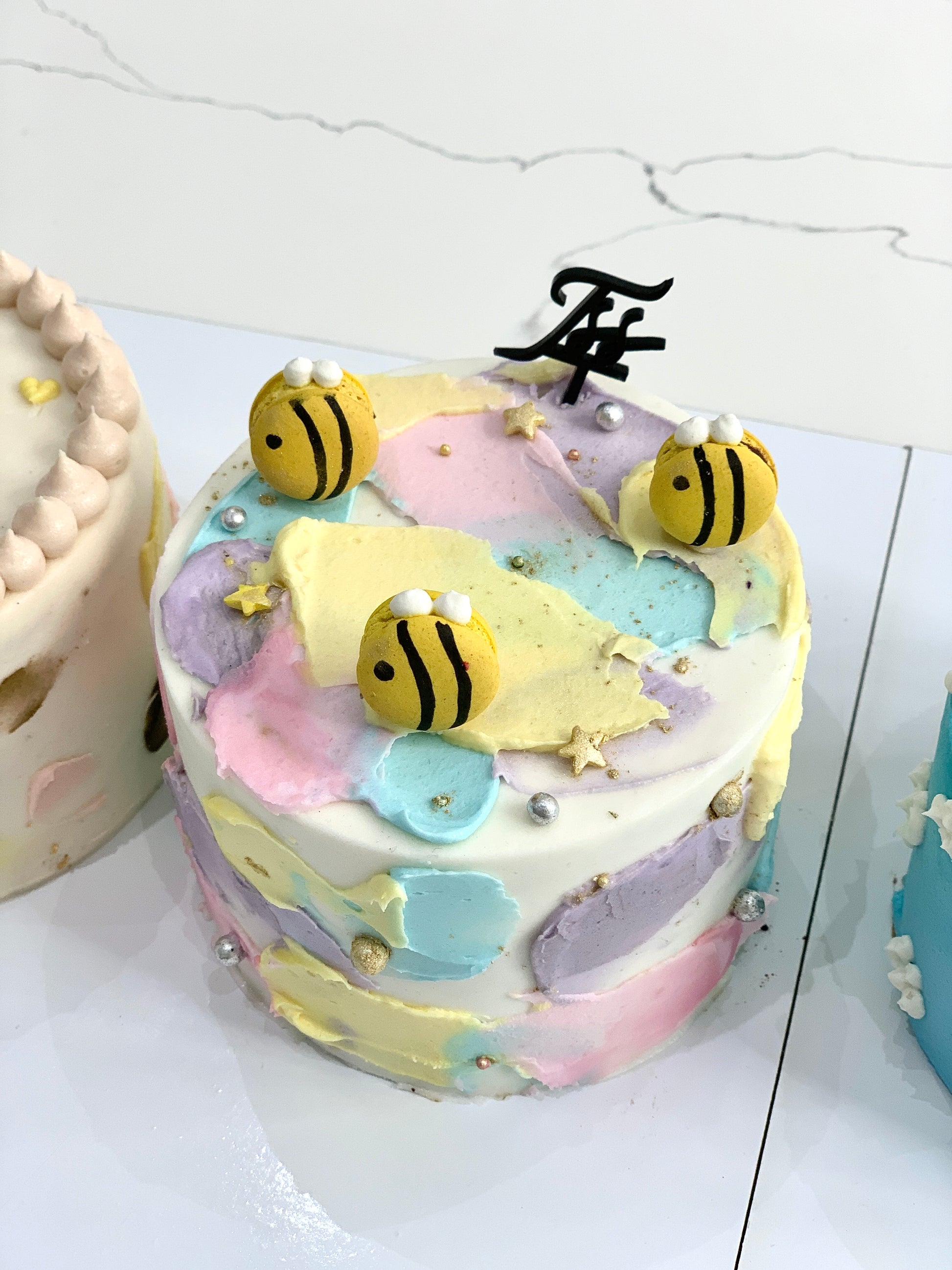 Colorful bento cakes from The Sinful Spoon featuring layered, decorative desserts with vibrant frosting and intricate designs.