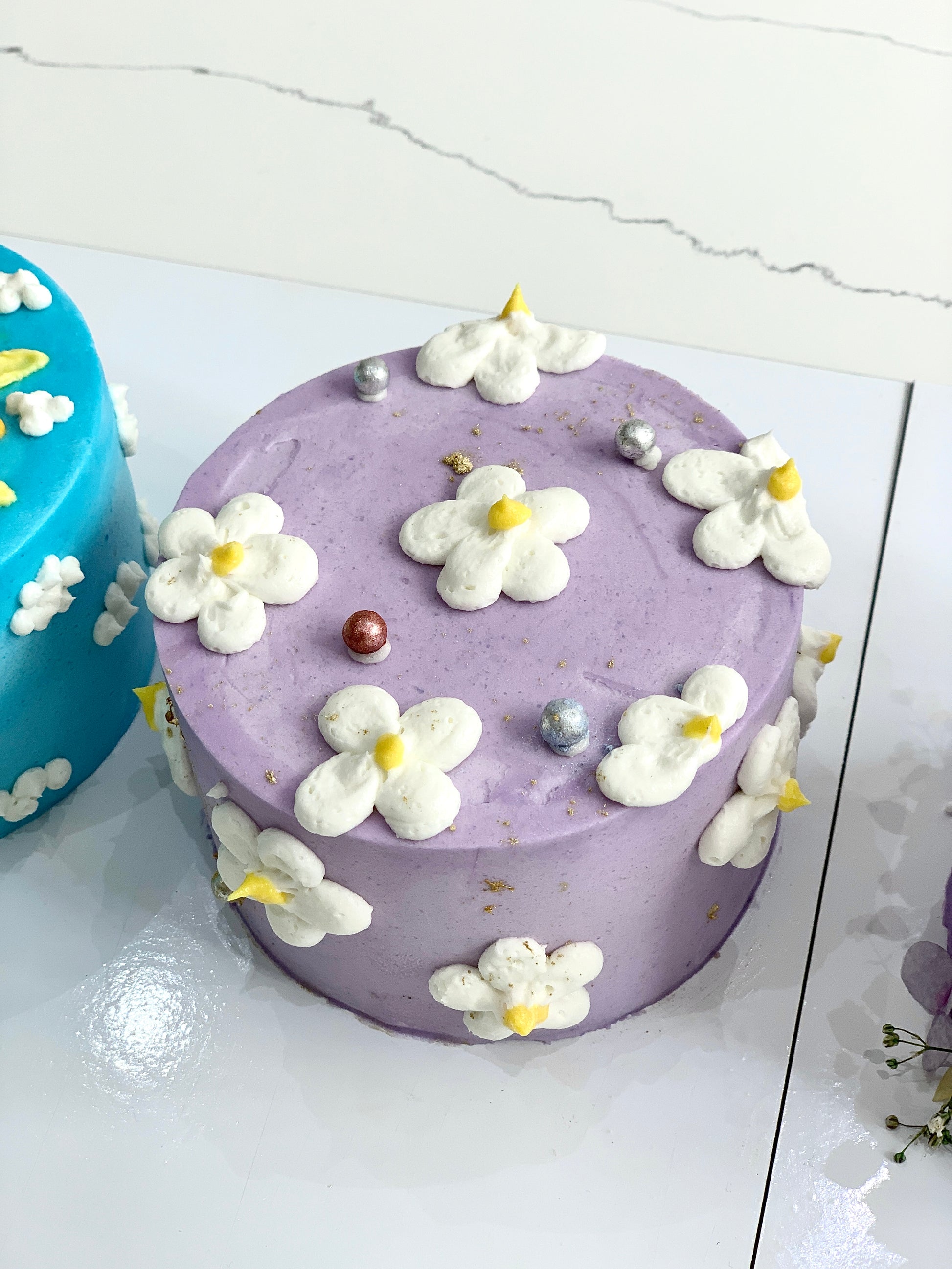 Colorful buttercream flower cake by The Sinful Spoon with intricate floral designs on a decorated cake stand.