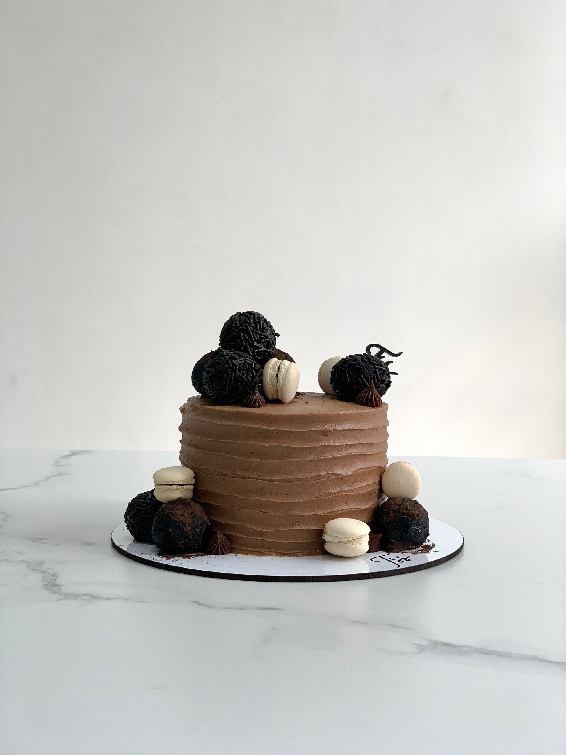 Slice of classic layered cake from The Sinful Spoon, showcasing rich frosting and colorful decorations on a white plate.