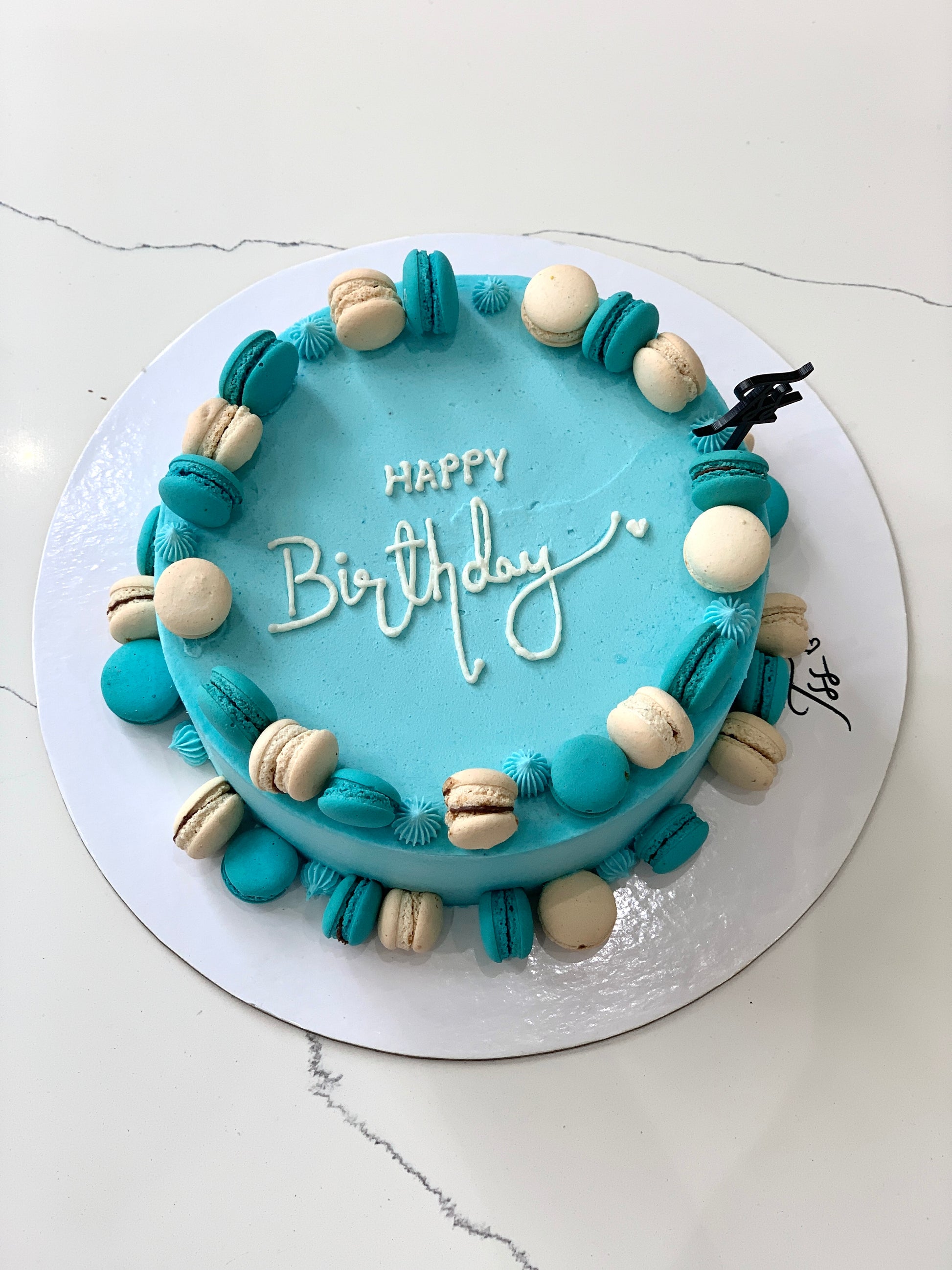 A classic cake from The Sinful Spoon featuring layered frosting and decorative toppings on a white plate.