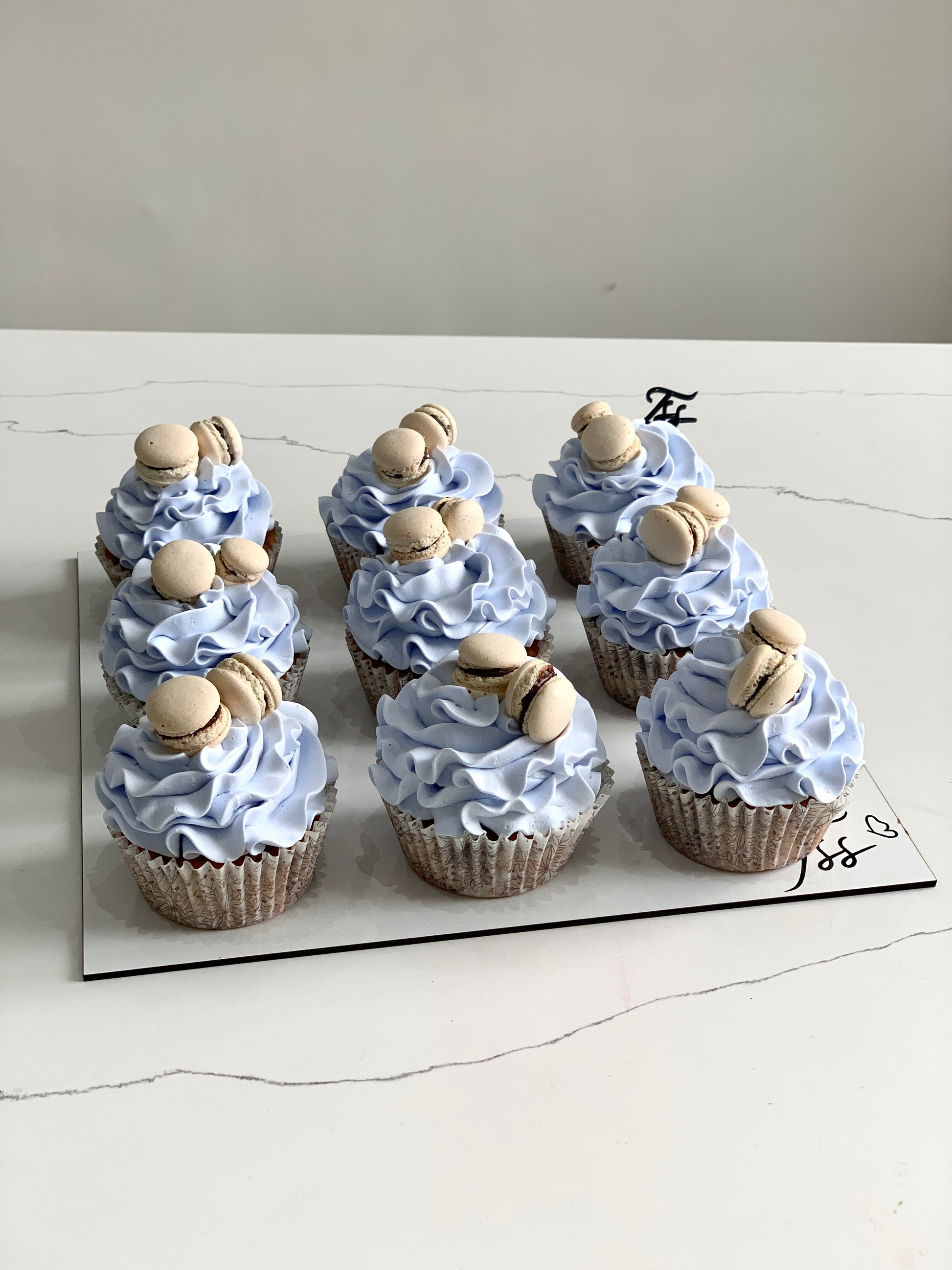 Assorted cupcakes from The Sinful Spoon with colorful frosting and decorative toppings on a white plate.