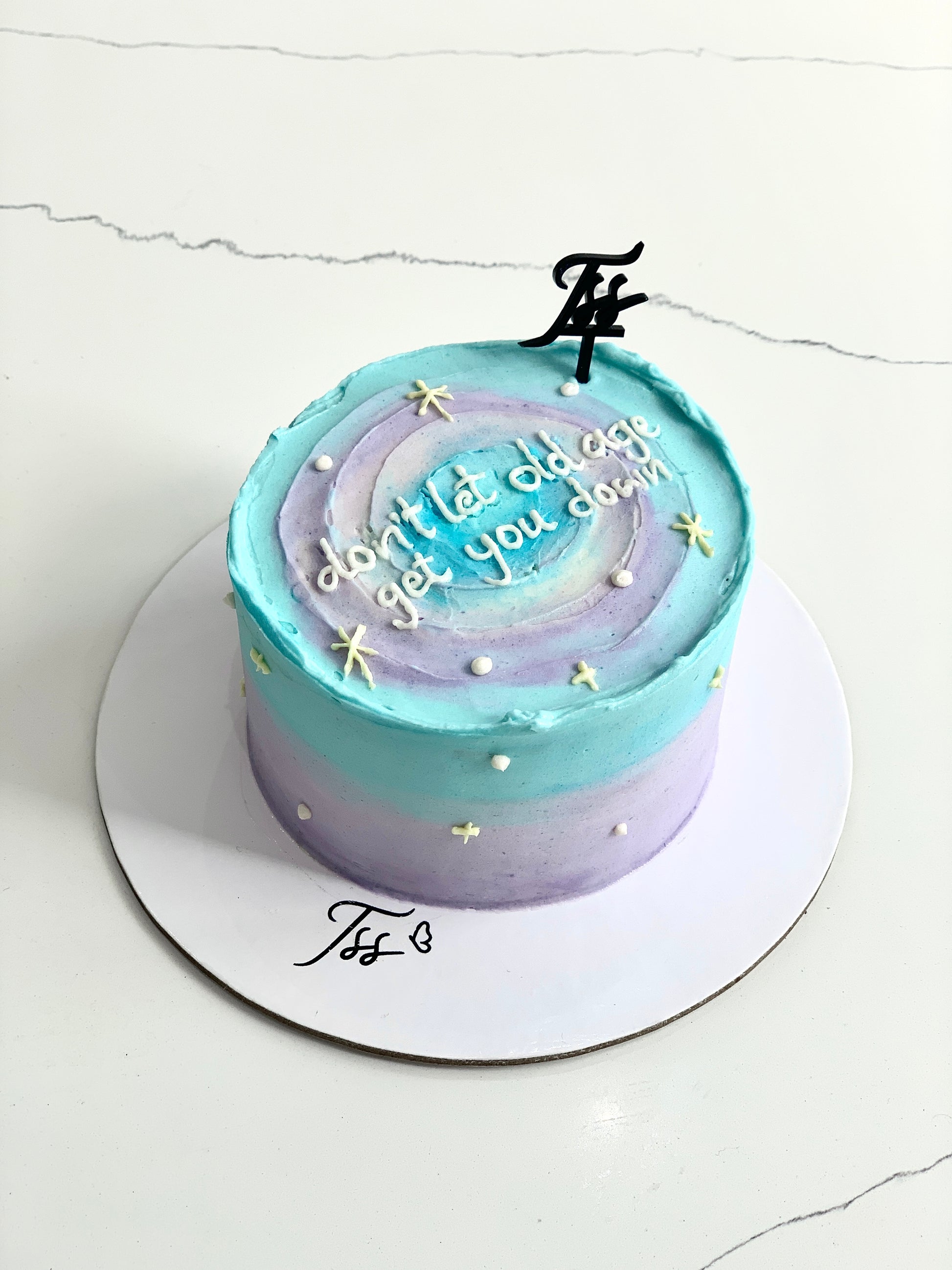 Colorful bento cakes from The Sinful Spoon with decorative toppings and vibrant icing, arranged on a white surface.