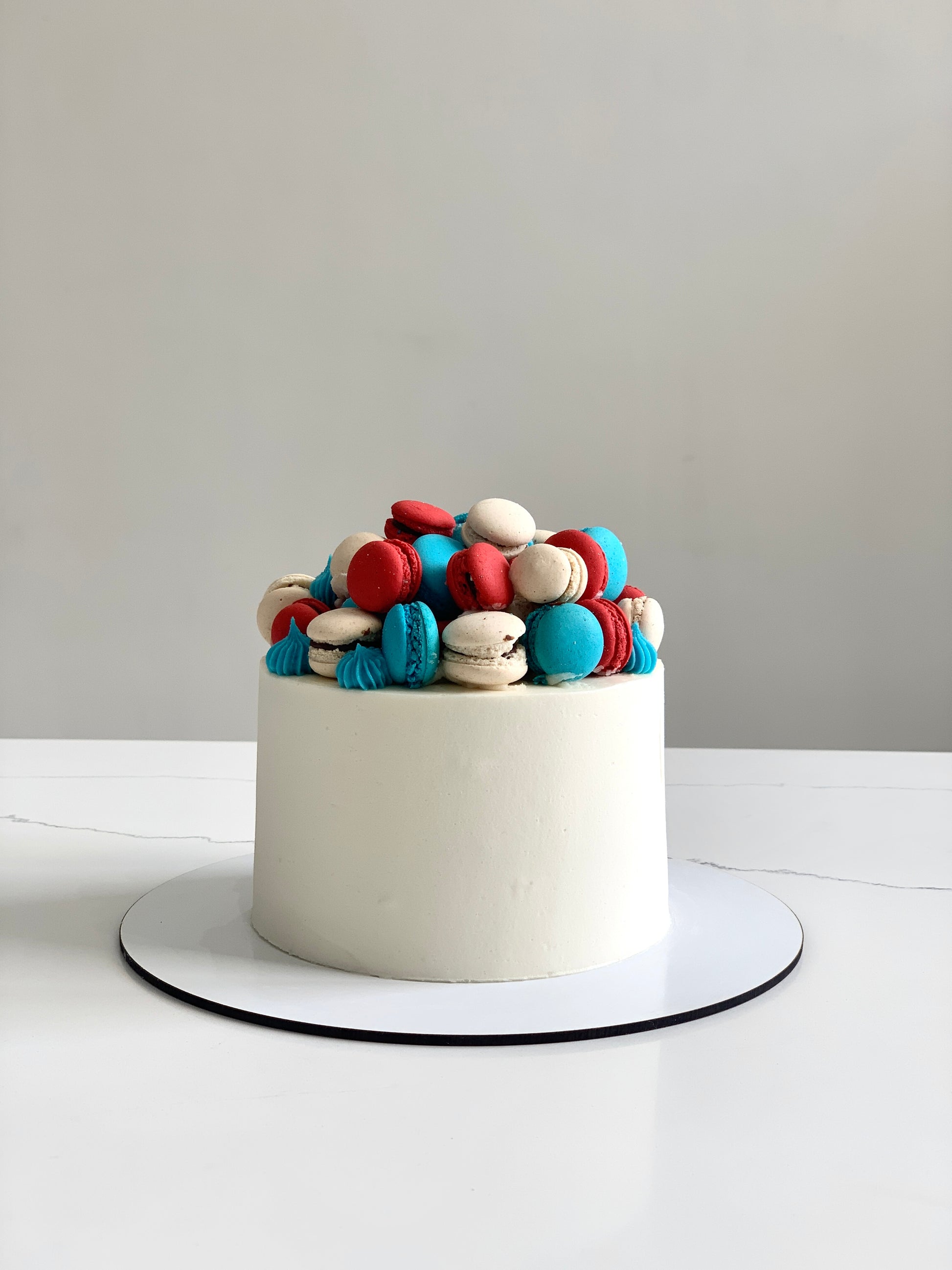 A classic cake from The Sinful Spoon featuring layered frosting and decorative toppings on a neutral plate.