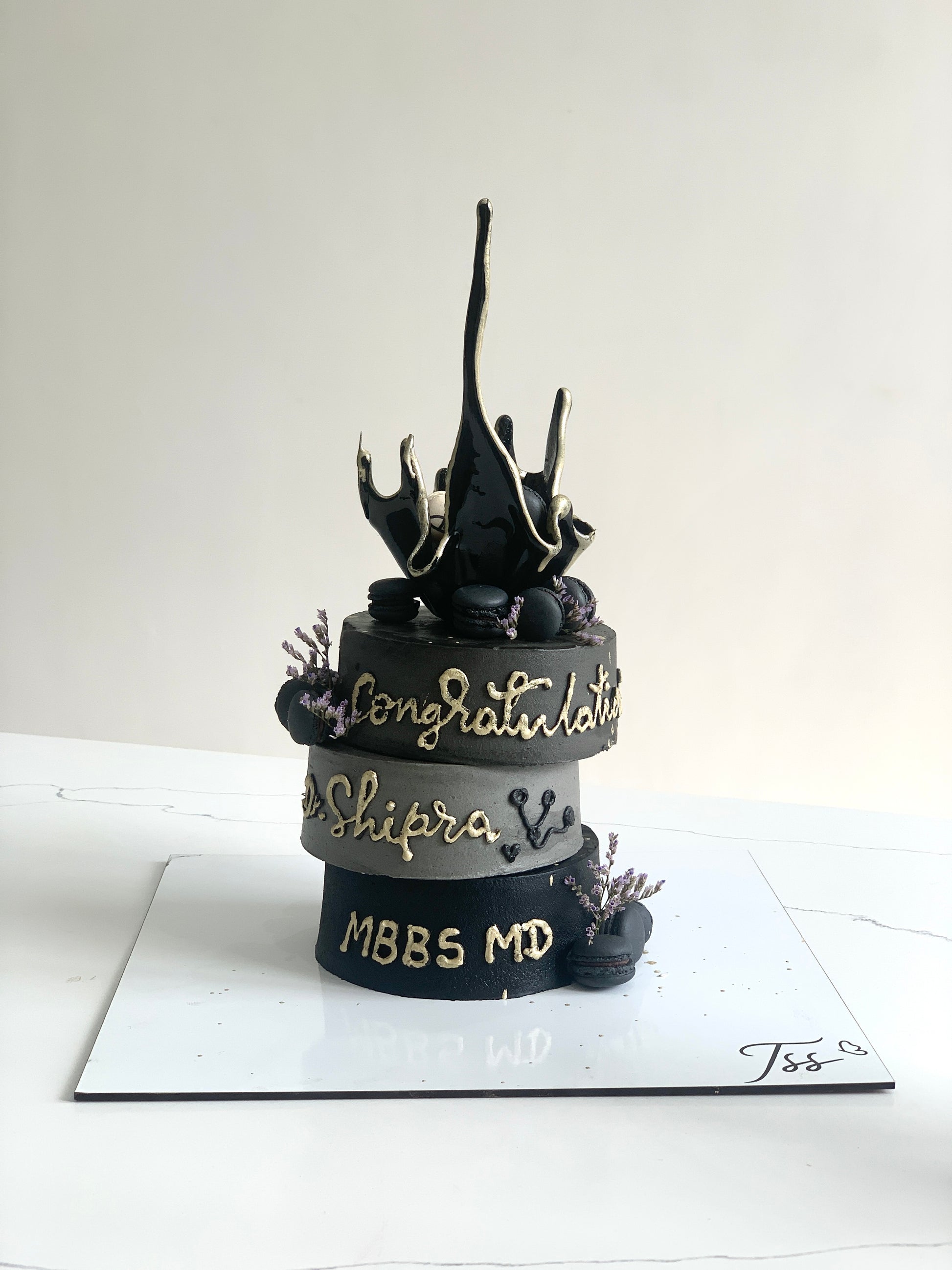 Asymmetrical cake from The Sinful Spoon with layered frosting and decorative toppings, displayed on a cake stand.
