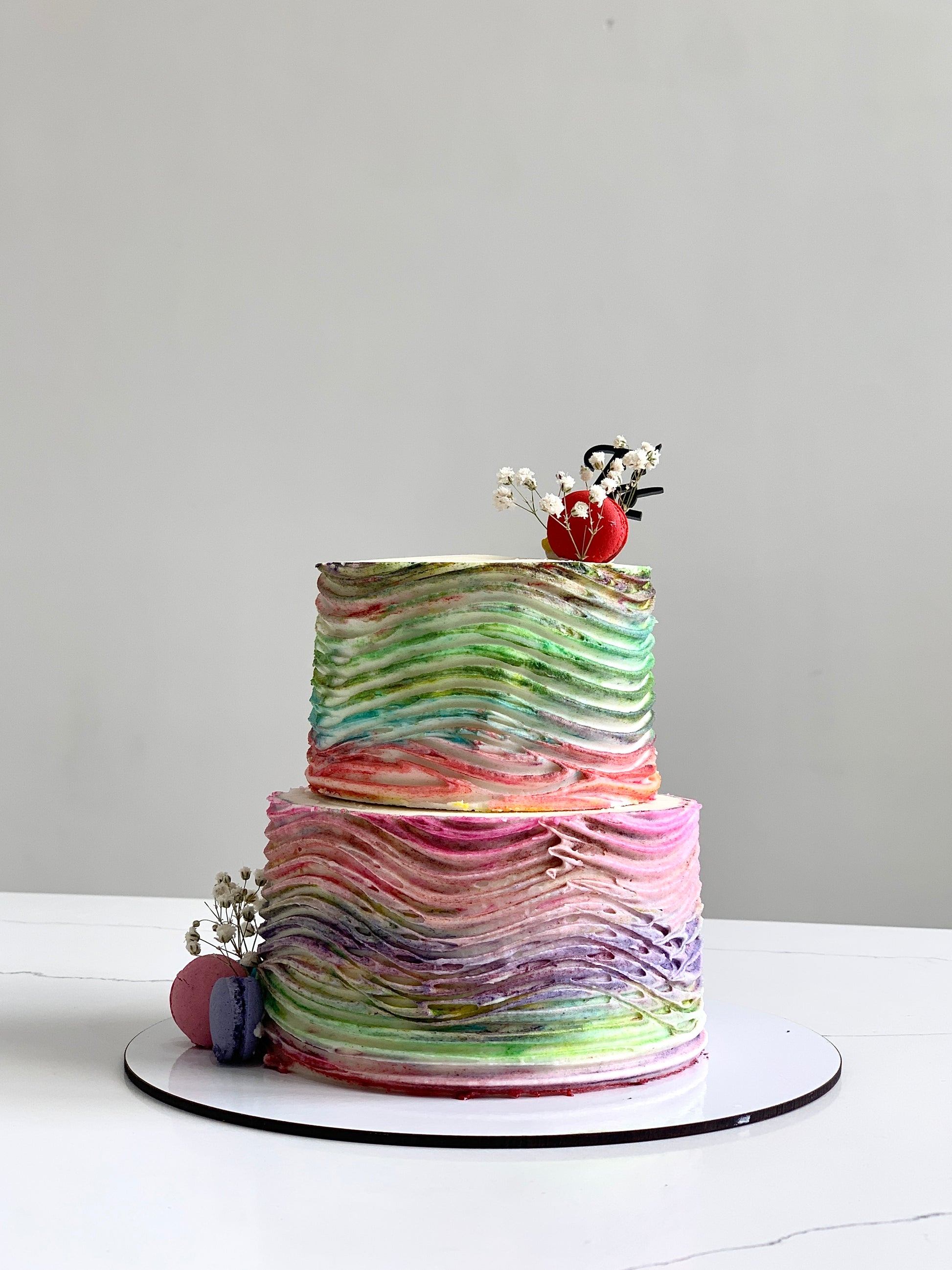 Miniature tier cakes from The Sinful Spoon, beautifully decorated with colorful icing and intricate details.