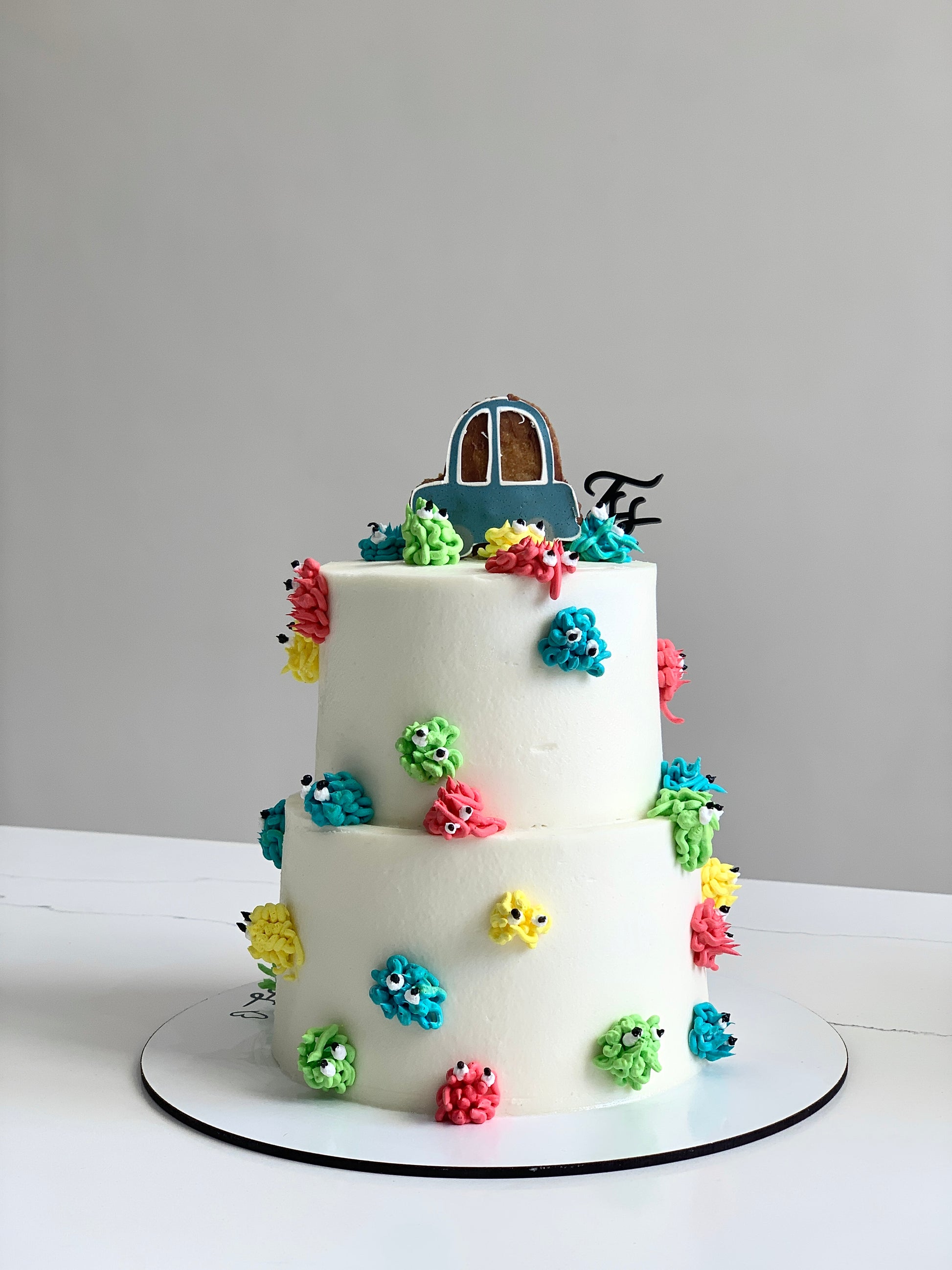 Miniature tier cakes from The Sinful Spoon, decorated with colorful frosting and intricate details, perfect for special occasions.