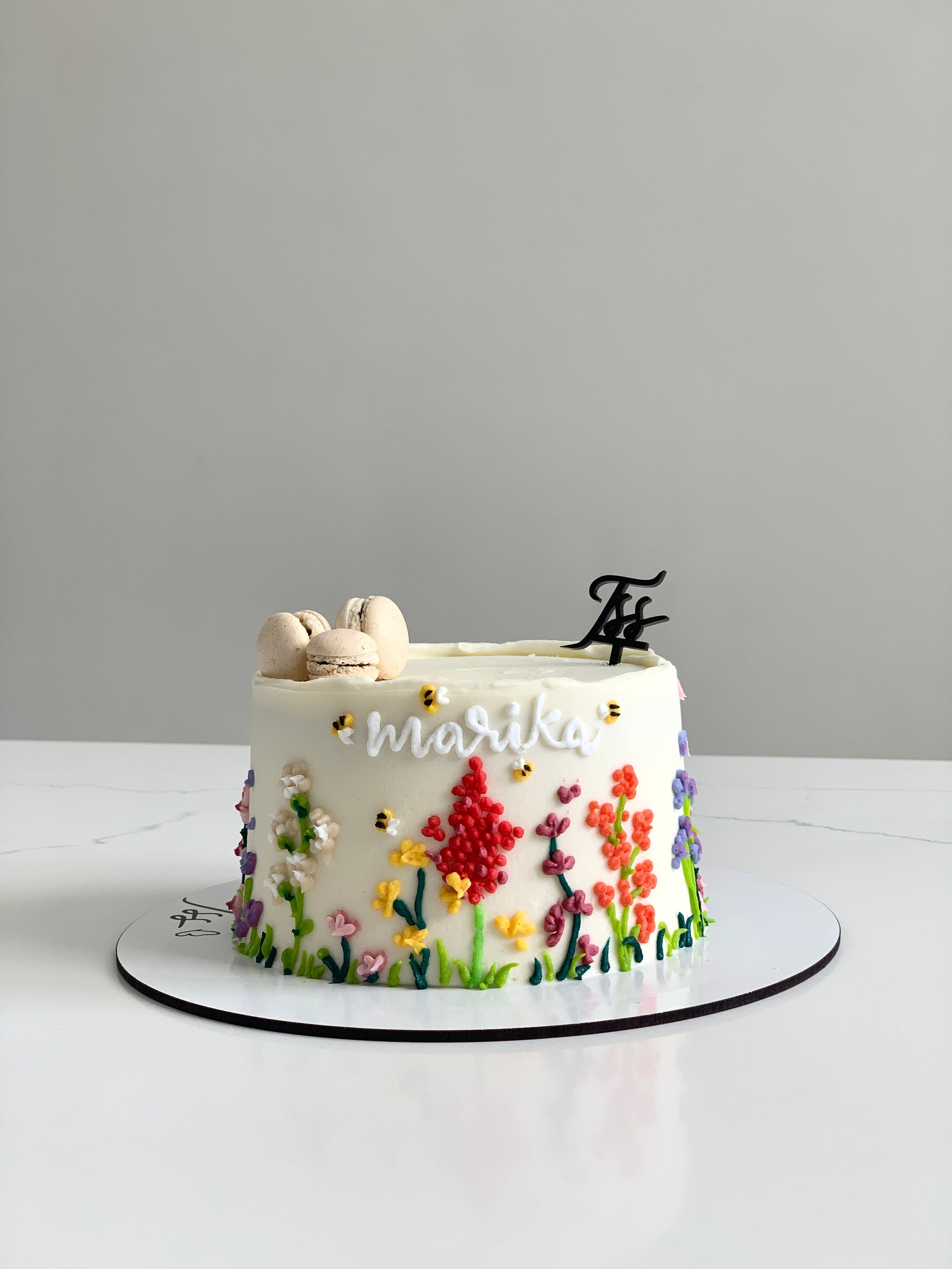Decorative Mother's Day cake from The Sinful Spoon with pink frosting and floral accents, perfect for celebrating moms.