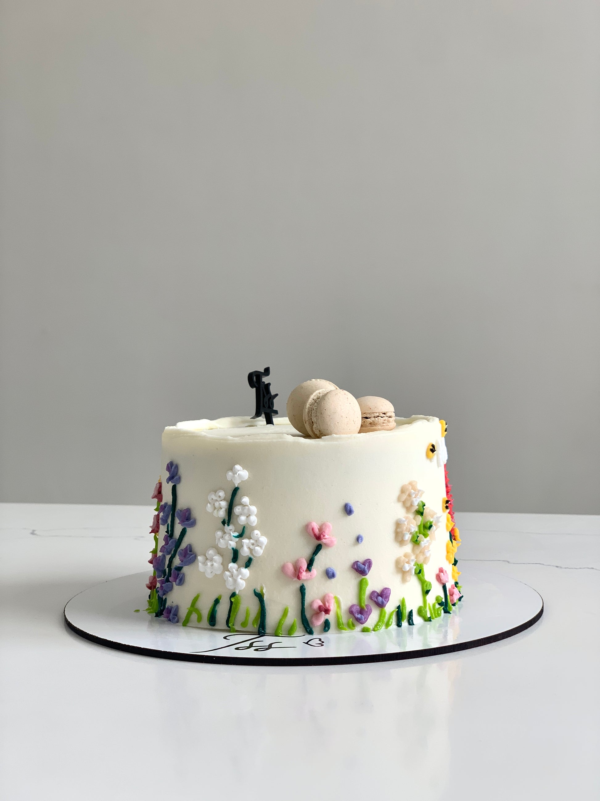 Decorative Mother's Day cake from The Sinful Spoon with floral frosting and festive design on a white cake stand.