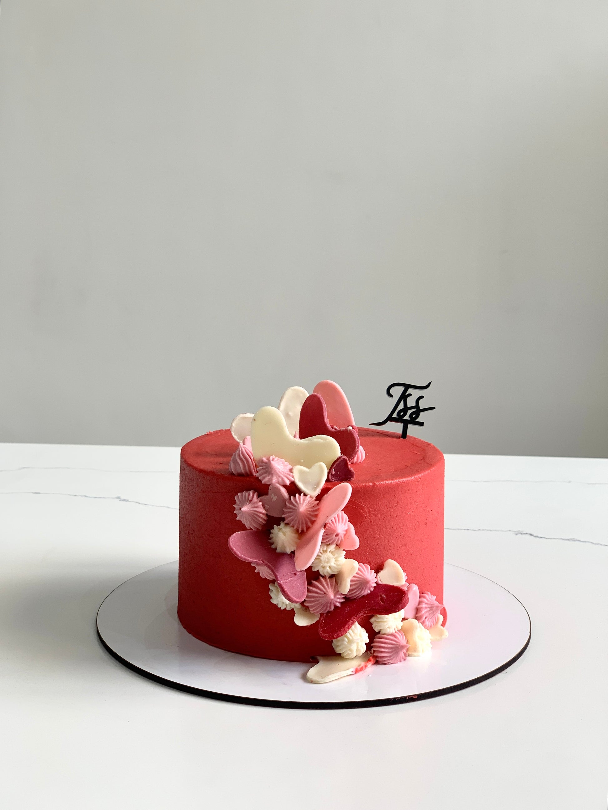 Valentine's Day cake from The Sinful Spoon with pink frosting and heart-shaped decorations on a white plate.