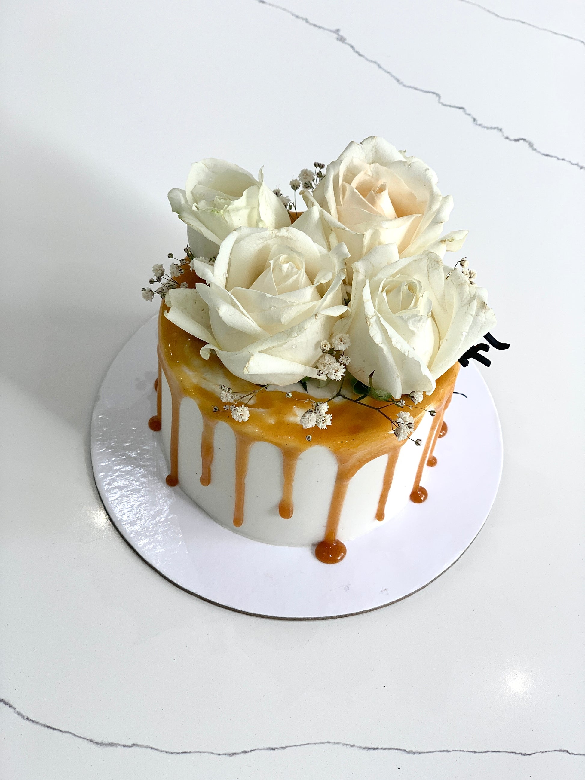 Fresh floral cakes by The Sinful Spoon featuring colorful edible flowers and intricate cake decorations on a white background.