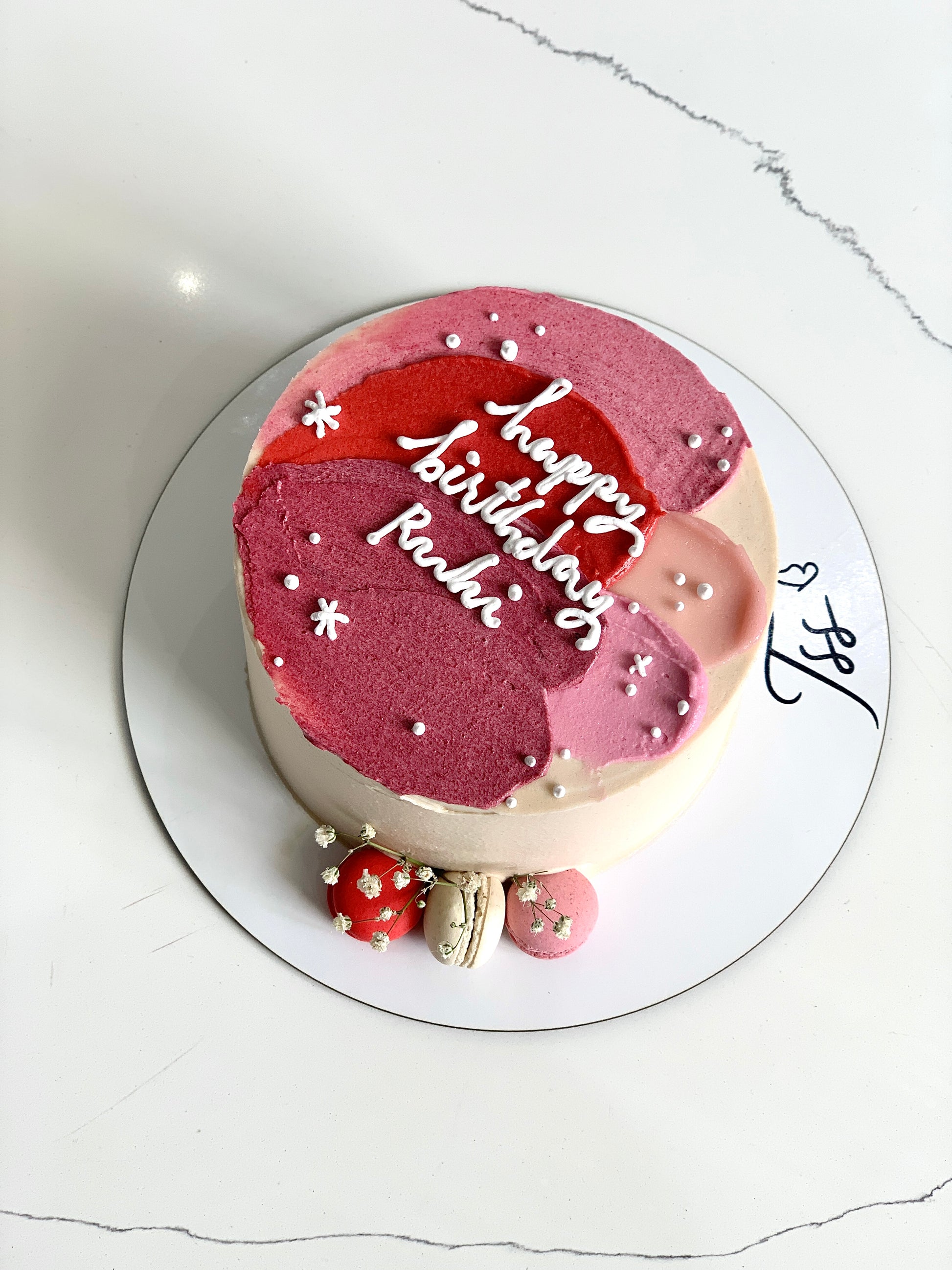 Assorted colorful Bento Cakes from The Sinful Spoon with decorative toppings and vibrant icing on a white plate.