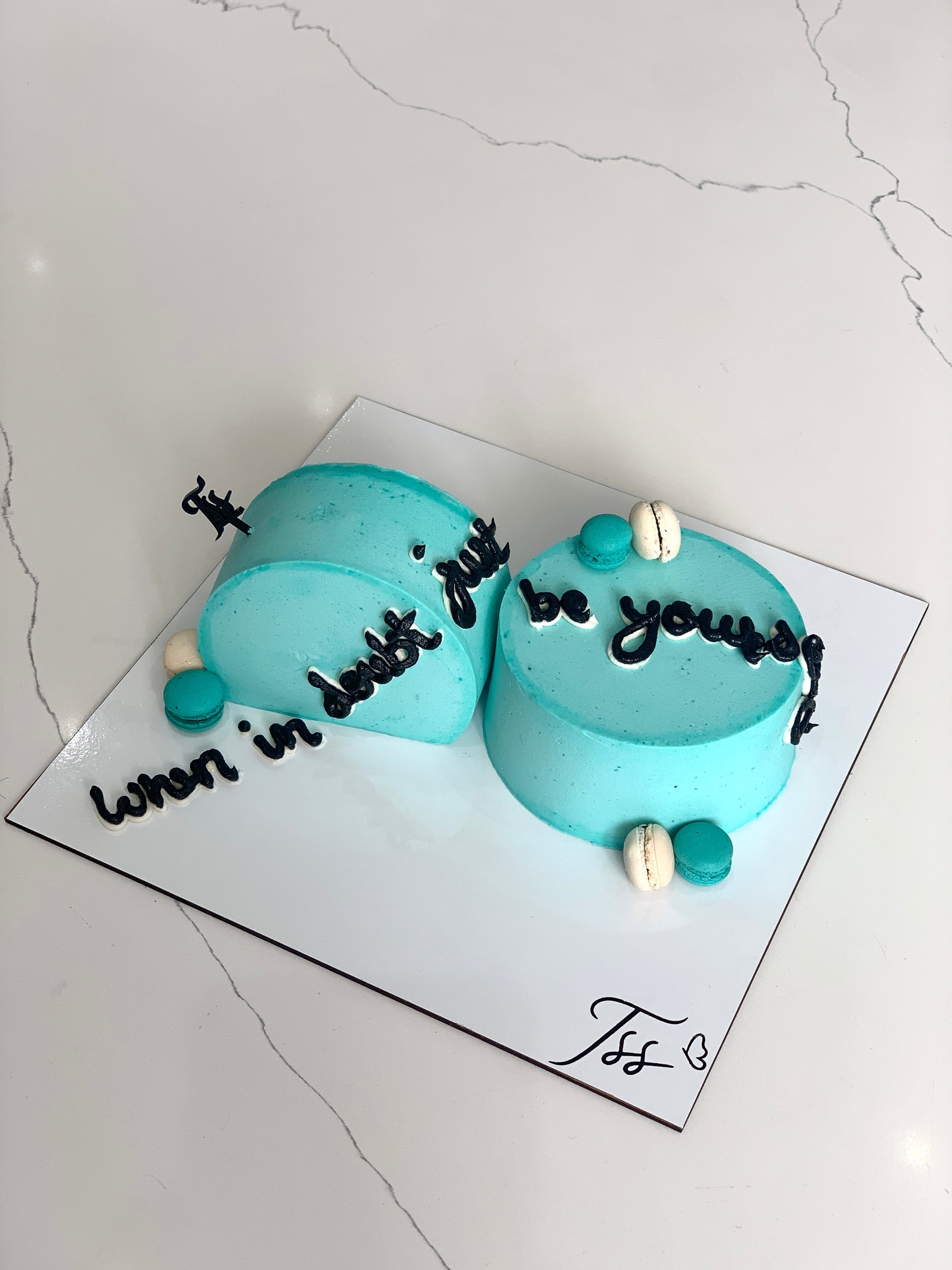 Inverted cakes from The Sinful Spoon displayed on a cake stand with colorful frosting and decorative toppings.