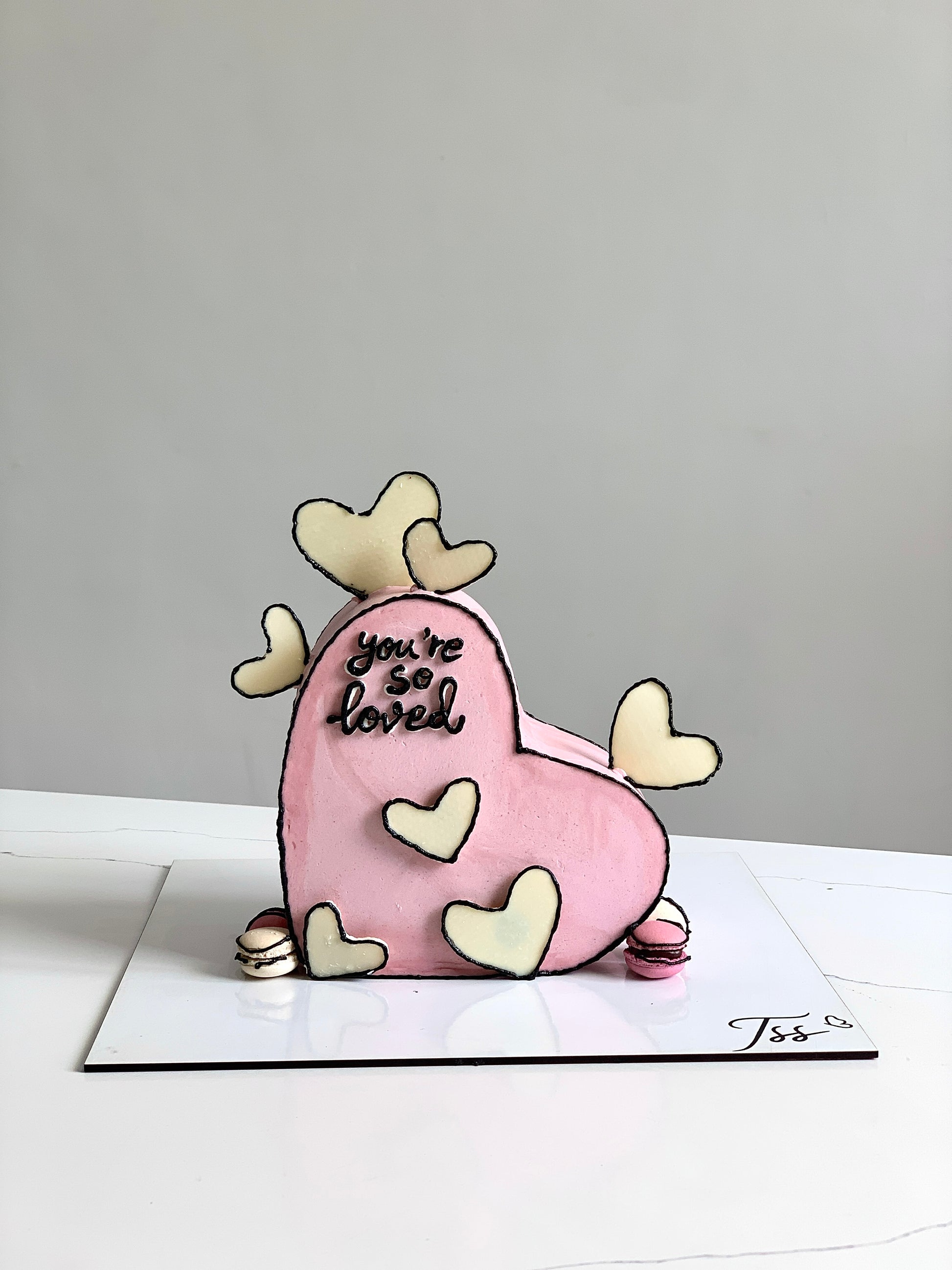 Valentine's Day cake from The Sinful Spoon with pink frosting and decorative heart-shaped toppings.