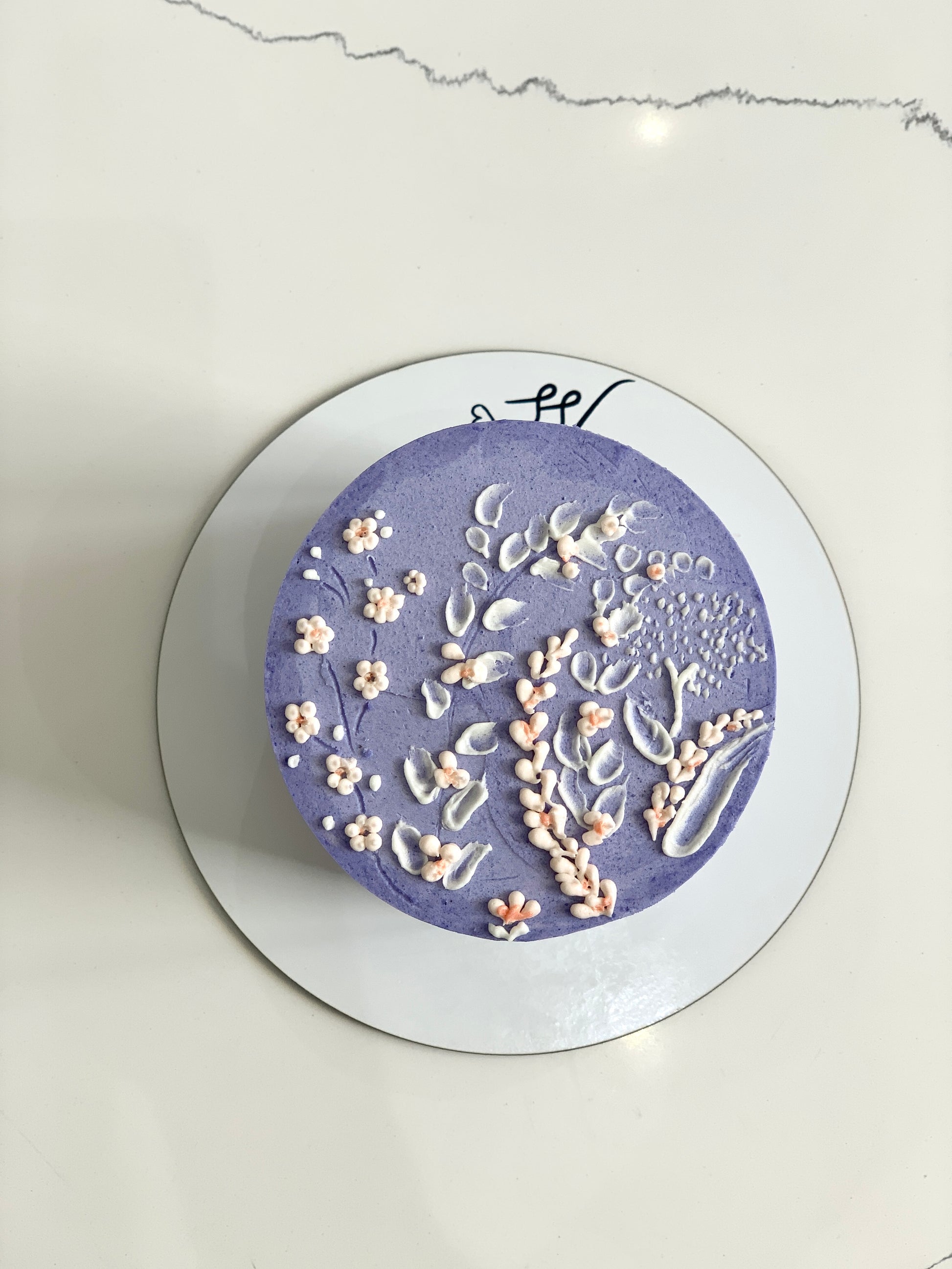 Decorative buttercream flower cake by The Sinful Spoon with colorful floral designs on a layered cake.