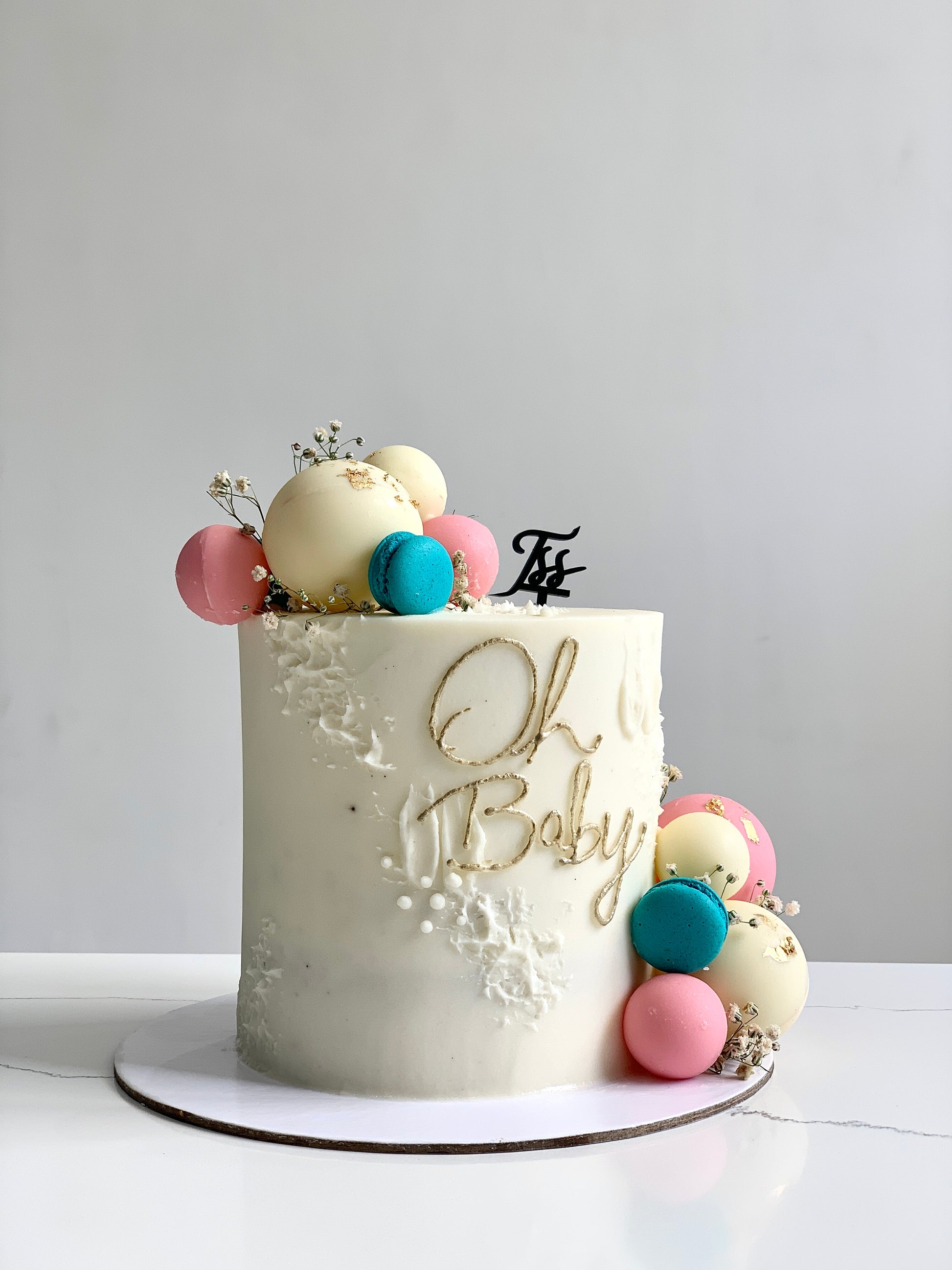 Decorative baby shower cake from The Sinful Spoon featuring pastel colors, baby-themed decorations, and intricate fondant details.