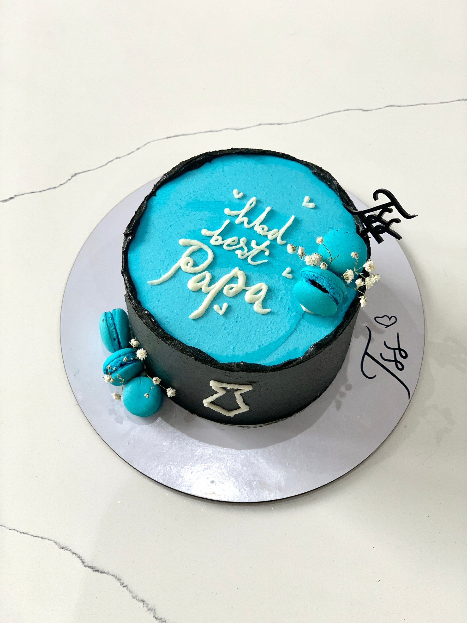 Decorative Father's Day cake from The Sinful Spoon with chocolate frosting and festive toppings, perfect for celebrating dad.