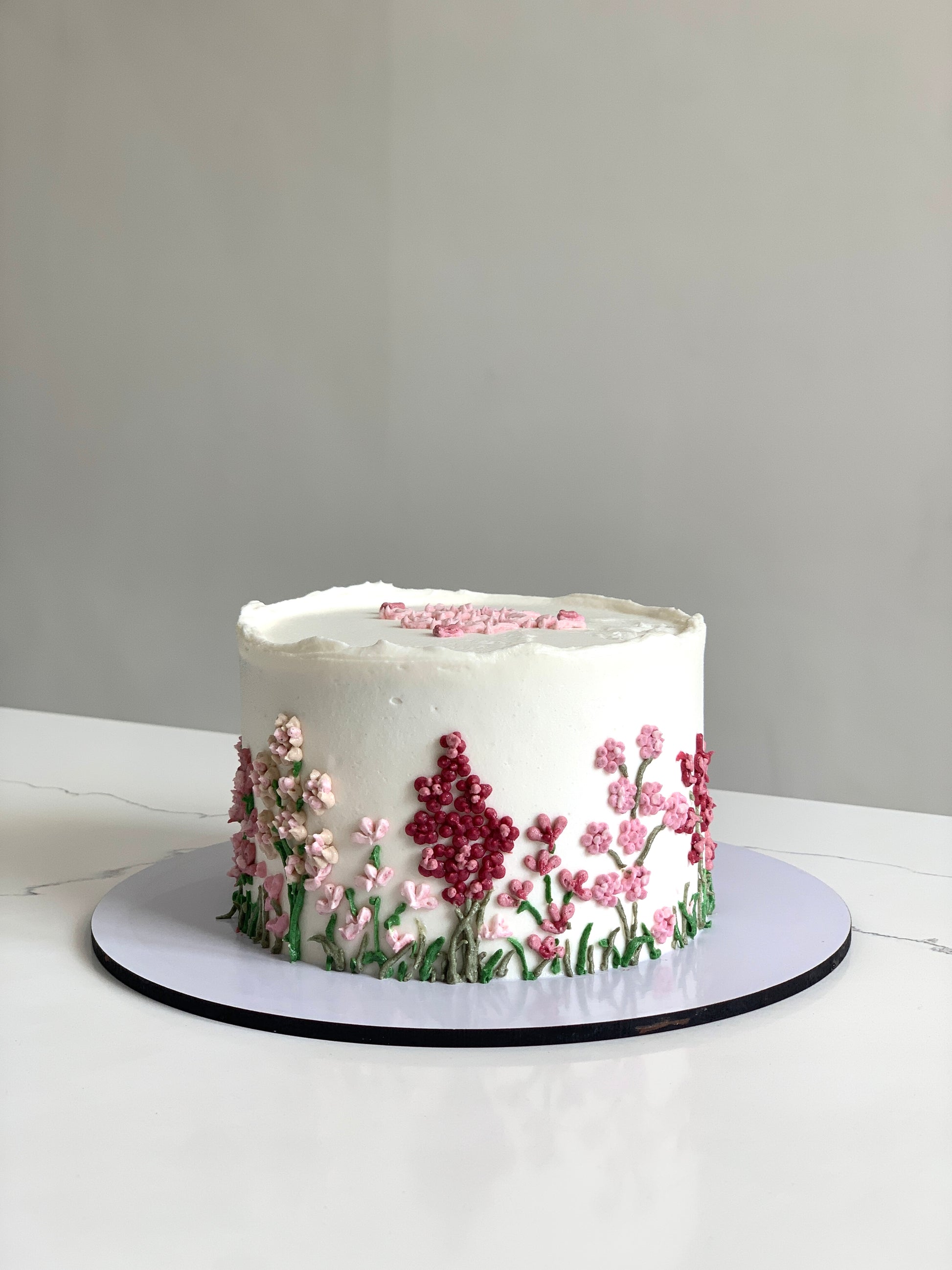 Decorative Mother's Day cake from The Sinful Spoon with floral frosting and festive design, perfect for celebrating moms.