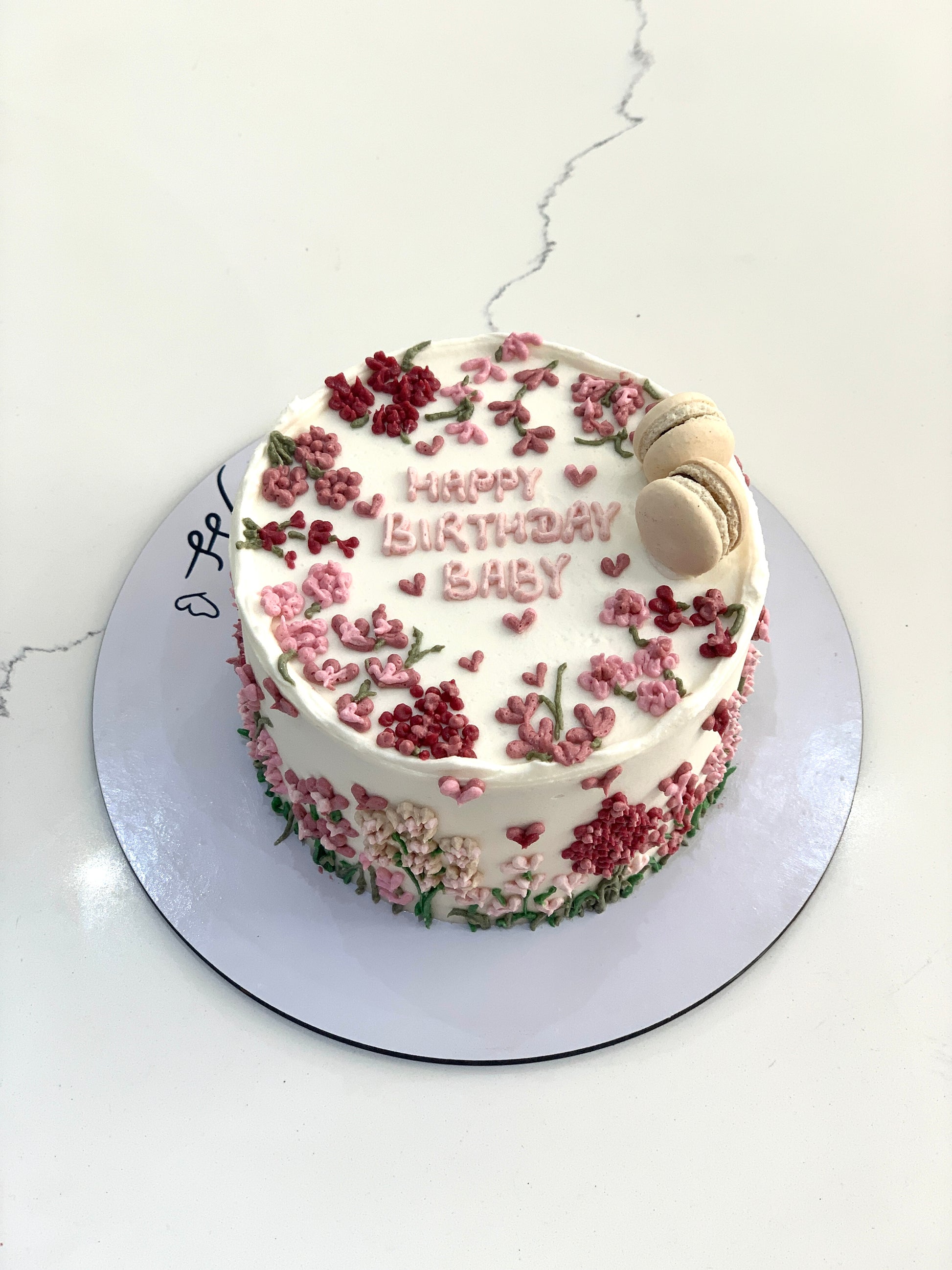 Decorative buttercream flower cakes by The Sinful Spoon featuring vibrant, handcrafted floral designs on a cake.