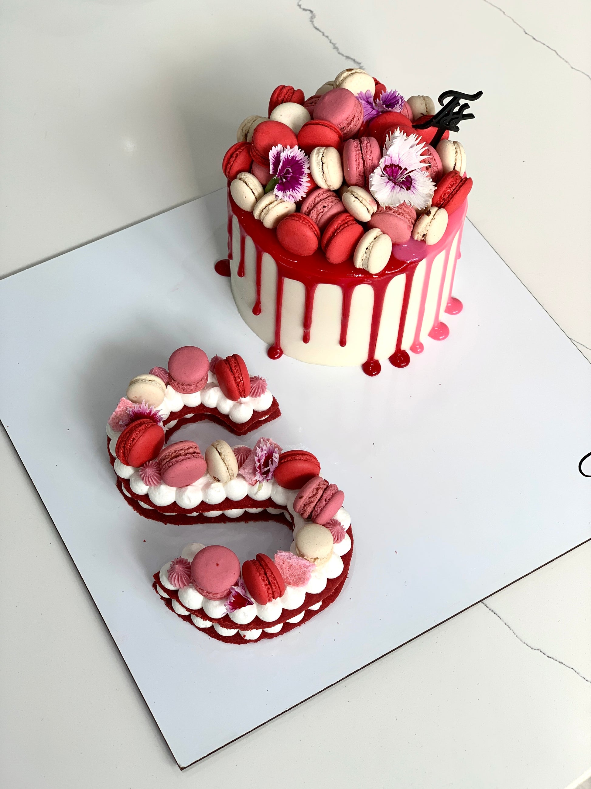 Assorted combo cakes from The Sinful Spoon with colorful frosting and decorative toppings on a wooden platter.