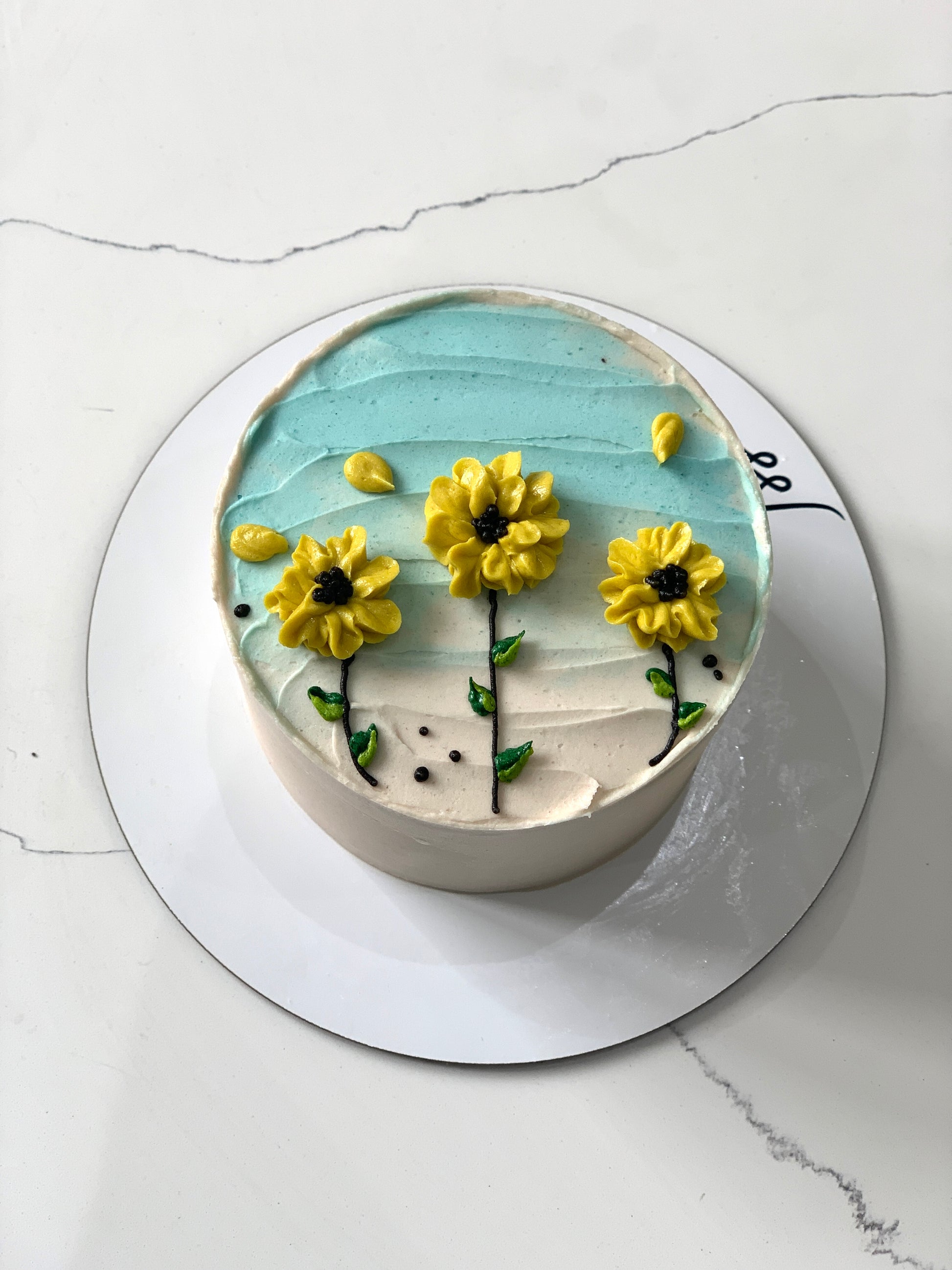 Decorative buttercream flower cake by The Sinful Spoon with colorful floral designs on a white cake.