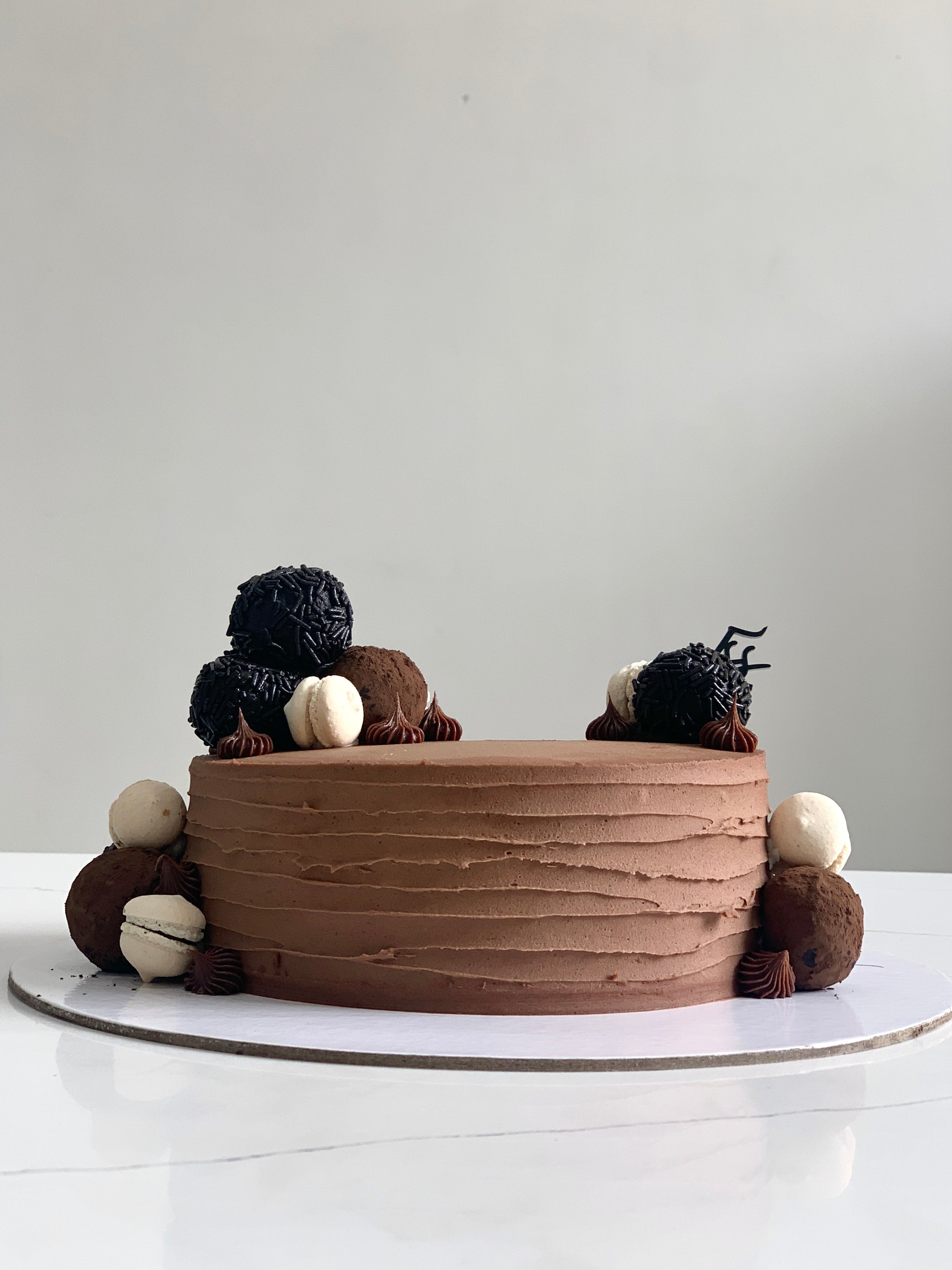 Slice of classic layered cake from The Sinful Spoon featuring creamy frosting and colorful decorations on a white plate.