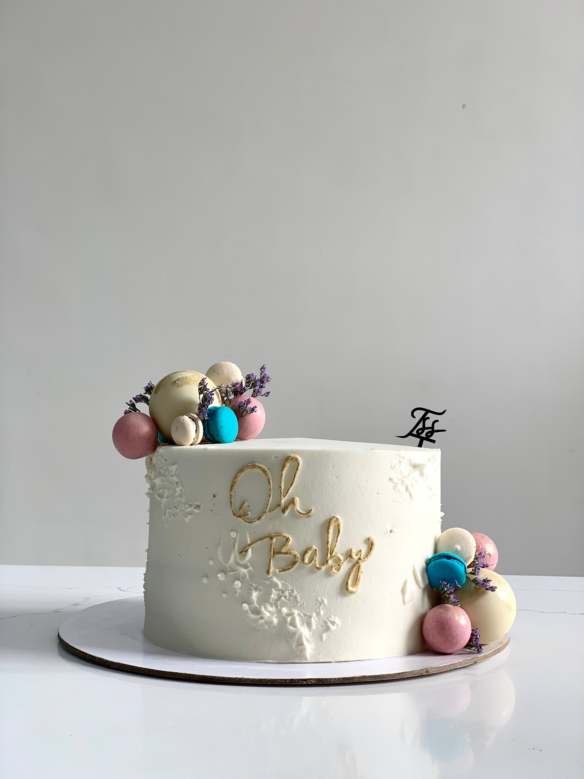 Decorative baby shower cake with pastel-colored frosting and cute baby-themed toppers by The Sinful Spoon.